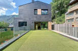 Modern architectural marvel showcasing a sleek facade with dark gray tiles and expansive glass windows.