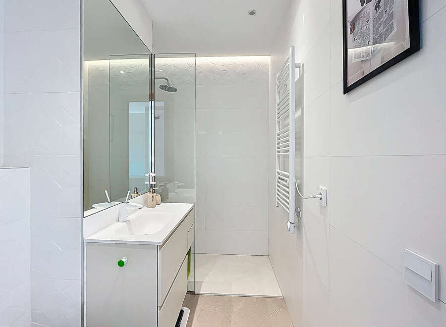 Discover a modern bathroom with sleek white tiles and a minimalist design.