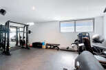 Step into your personal fitness sanctuary! This home gym boasts a comprehensive setup, including a Smith machine, weight bench, and various exercise equipment.