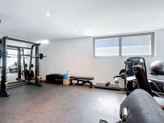 Step into your personal fitness sanctuary! This home gym boasts a comprehensive setup, including a Smith machine, weight bench, and various exercise equipment.