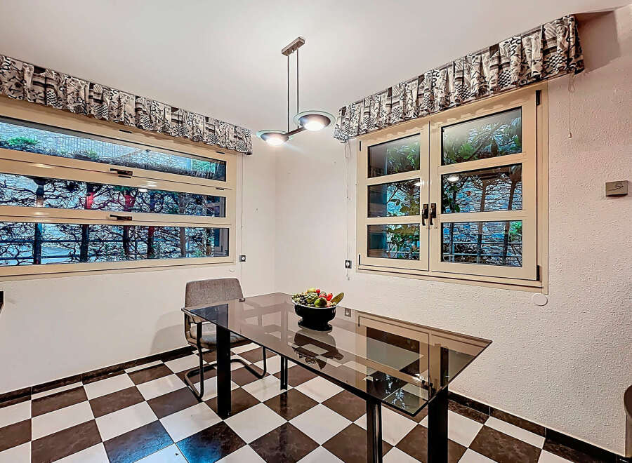 This charming kitchen features a sleek glass-top table, perfect for dining or working.