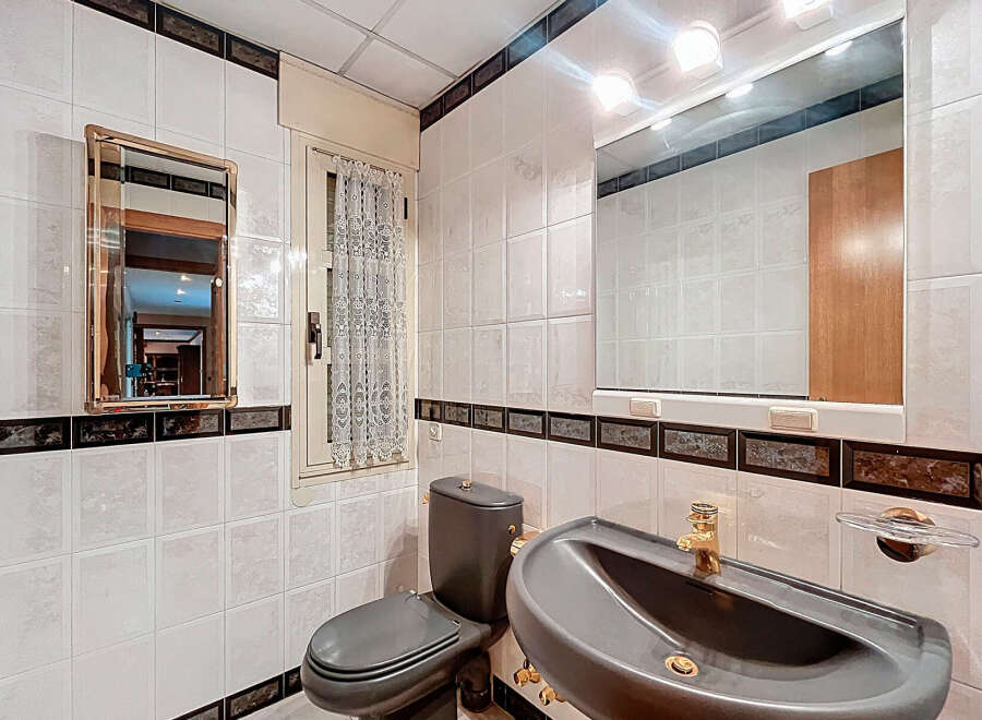 This bathroom features a stylish design with white tiles and dark accents.