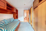 Discover a cozy bedroom with a nautical theme, featuring a comfortable striped bed and stylish built-in wooden storage.