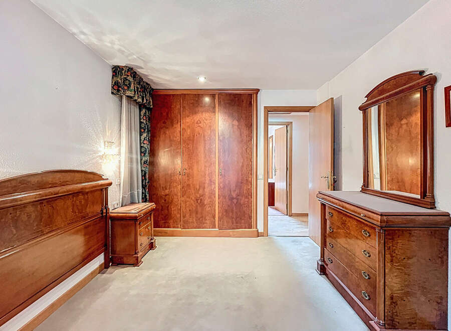 Elegant bedroom featuring rich wooden furniture, including a large wardrobe, dresser, and bed frame.