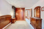 Elegant bedroom featuring rich wooden furniture, including a large wardrobe, dresser, and bed frame.