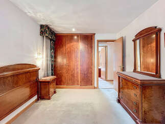 Elegant bedroom featuring rich wooden furniture, including a large wardrobe, dresser, and bed frame.