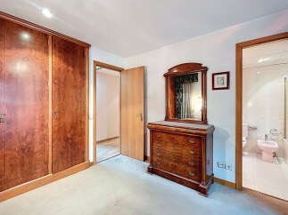 Discover the charm of this well-appointed bedroom, featuring a stunning wooden wardrobe and a classic dresser with a mirror.