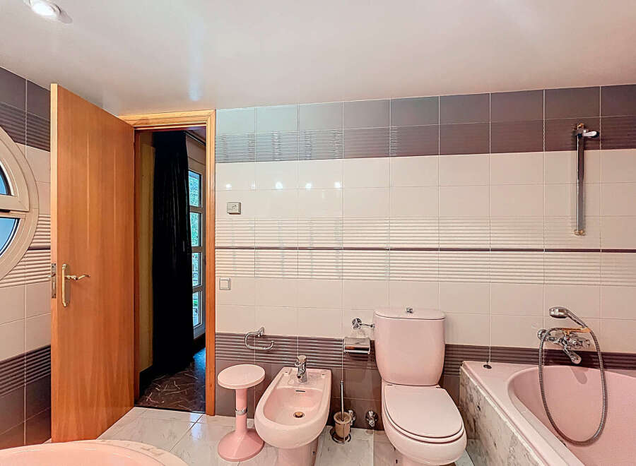 Step into this charming bathroom featuring a unique pink toilet and bidet, adding a touch of retro flair.