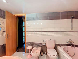 Step into this charming bathroom featuring a unique pink toilet and bidet, adding a touch of retro flair.