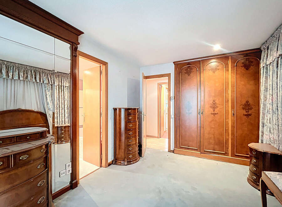 Step into a spacious bedroom with classic wooden furniture.
