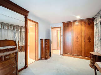 Step into a spacious bedroom with classic wooden furniture.