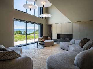 This luxurious living room features a plush, modular sofa arranged around a soft, textured rug, creating a cozy and inviting space.