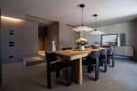 This dining room features a solid wood table paired with modern black chairs, illuminated by sleek pendant lights.