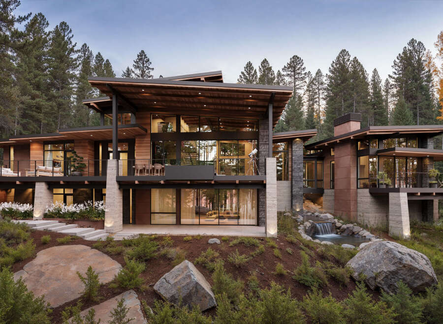 This modern mountain home boasts expansive windows, a private balcony, and a serene waterfall feature.
