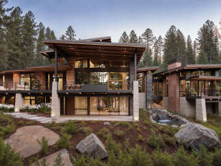 This modern mountain home boasts expansive windows, a private balcony, and a serene waterfall feature.