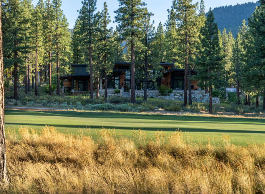 Nestled amidst towering trees and overlooking a pristine golf course, this modern home offers a serene escape.