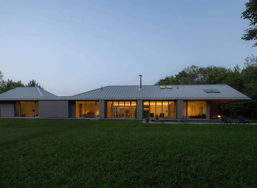 This stunning modern home boasts a sleek, low-profile design with expansive windows offering breathtaking views of the surrounding landscape.