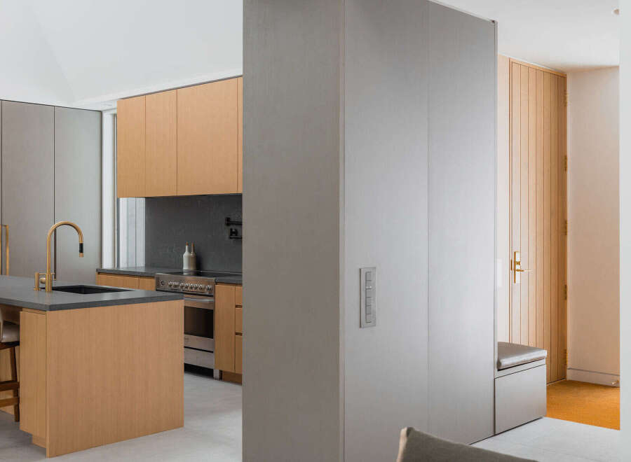 This stunning modern kitchen boasts sleek gray and light wood cabinetry, complemented by a stylish island and gold-toned fixtures.