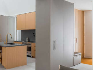 This stunning modern kitchen boasts sleek gray and light wood cabinetry, complemented by a stylish island and gold-toned fixtures.