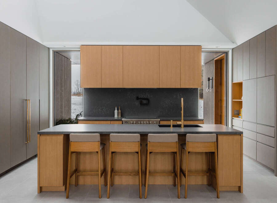 This stunning kitchen boasts a sleek, modern design with light oak cabinetry, complemented by dark gray countertops and a sophisticated backsplash.