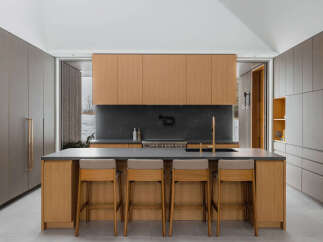 This stunning kitchen boasts a sleek, modern design with light oak cabinetry, complemented by dark gray countertops and a sophisticated backsplash.