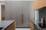 This stunning kitchen boasts sleek, gray cabinetry with brushed gold hardware, complemented by warm wood tones on the lower cabinets and countertops.