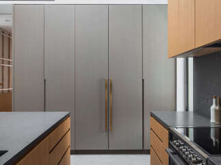 This stunning kitchen boasts sleek, gray cabinetry with brushed gold hardware, complemented by warm wood tones on the lower cabinets and countertops.