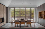 This stunning modern home boasts a spacious dining area with floor-to-ceiling windows offering breathtaking views of a snow-dusted forest.