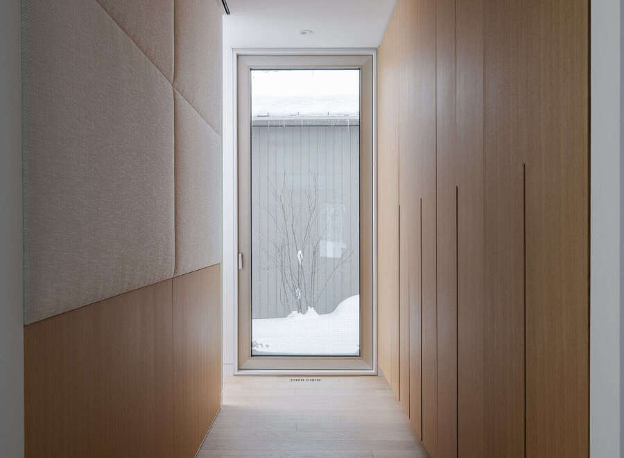 This modern hallway boasts a sleek design with light wood paneling and a textured fabric wall accent.
