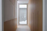 This modern hallway boasts a sleek design with light wood paneling and a textured fabric wall accent.