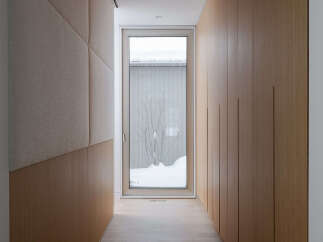This modern hallway boasts a sleek design with light wood paneling and a textured fabric wall accent.