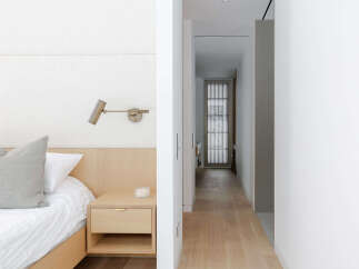 This modern bedroom features a minimalist design with a light wood nightstand and a white upholstered headboard.