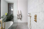 This stunning bathroom boasts a freestanding bathtub, a walk-in shower with brass fixtures, and a sleek glass partition.