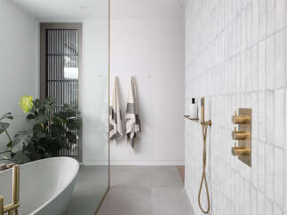 This stunning bathroom boasts a freestanding bathtub, a walk-in shower with brass fixtures, and a sleek glass partition.