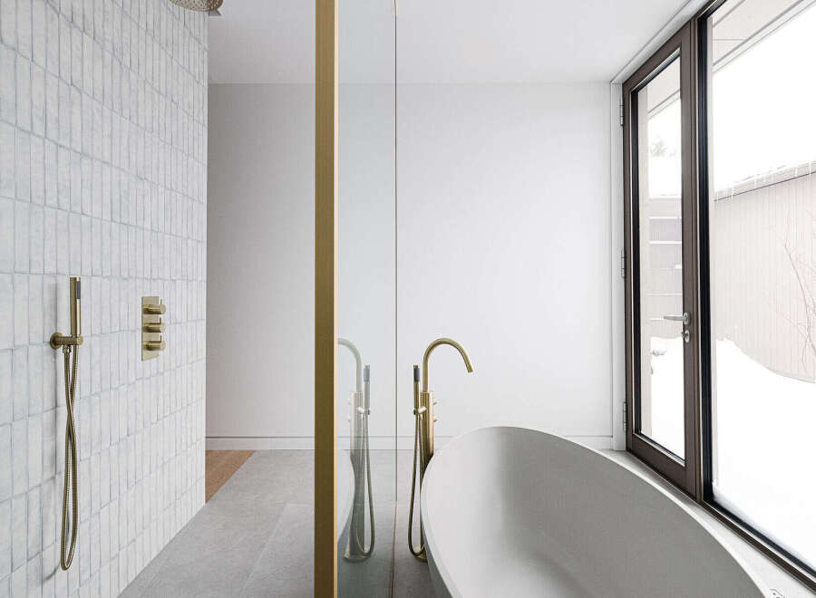 This luxurious bathroom boasts a freestanding bathtub, a walk-in shower with rainfall shower head, and sleek gold fixtures.