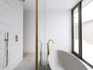 This luxurious bathroom boasts a freestanding bathtub, a walk-in shower with rainfall shower head, and sleek gold fixtures.