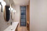 This modern bathroom boasts a sleek design with double vanities, oval mirrors, and minimalist lighting.