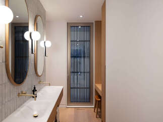 This modern bathroom boasts a sleek design with double vanities, oval mirrors, and minimalist lighting.