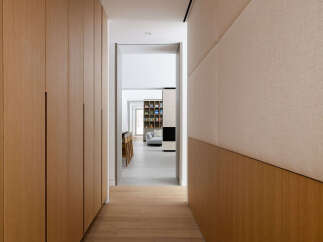 This hallway boasts a sleek and modern design, featuring light wood paneling and built-in cabinetry.