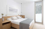 This minimalist bedroom boasts a light and airy feel, featuring a light wood platform bed with crisp white linens and a gray throw.
