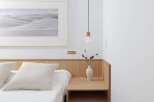 This serene bedroom boasts a minimalist aesthetic with a light oak wood headboard and nightstand, complemented by crisp white linens and a monochrome desert landscape print.