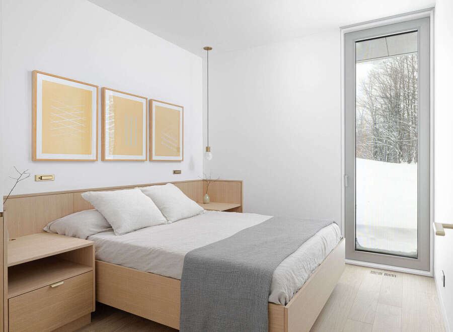 This minimalist bedroom boasts a light and airy feel, featuring a light wood platform bed with gray linen bedding and a sleek nightstand.