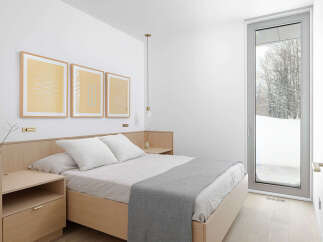 This minimalist bedroom boasts a light and airy feel, featuring a light wood platform bed with gray linen bedding and a sleek nightstand.