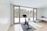 This stunning home gym boasts floor-to-ceiling windows showcasing a breathtaking snowy landscape, creating a serene and inspiring workout environment.