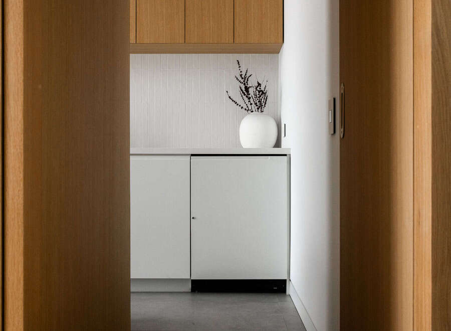 Modern kitchen features sleek white cabinetry and integrated appliances, complemented by light oak wood accents.