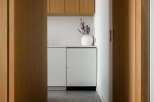 Modern kitchen features sleek white cabinetry and integrated appliances, complemented by light oak wood accents.
