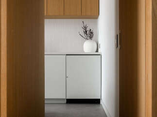 Modern kitchen features sleek white cabinetry and integrated appliances, complemented by light oak wood accents.