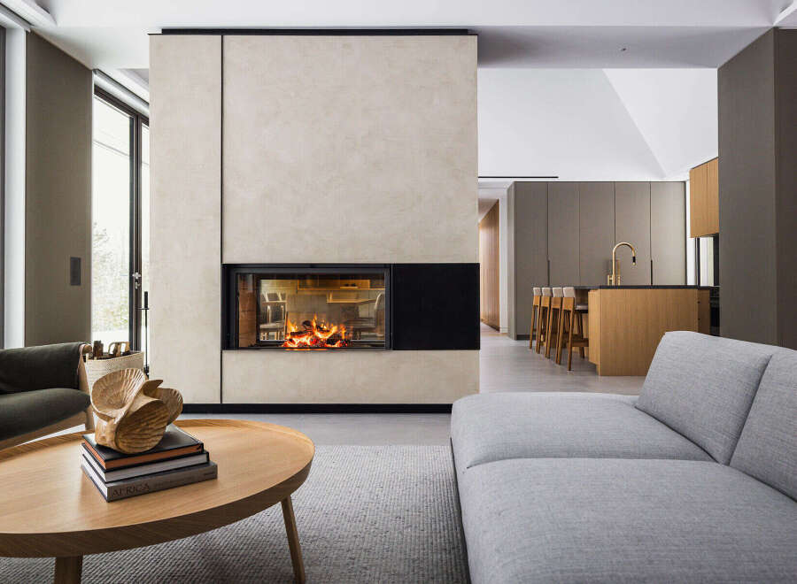 This stunning modern home boasts a sleek, minimalist design with a focal point of a contemporary fireplace encased in light beige plaster.
