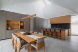 This stunning modern kitchen boasts a spacious island with bar seating, sleek gray and light wood cabinetry, and a large window offering scenic views.