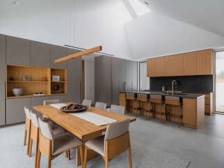 This stunning modern kitchen boasts a spacious island with bar seating, sleek gray and light wood cabinetry, and a large window offering scenic views.